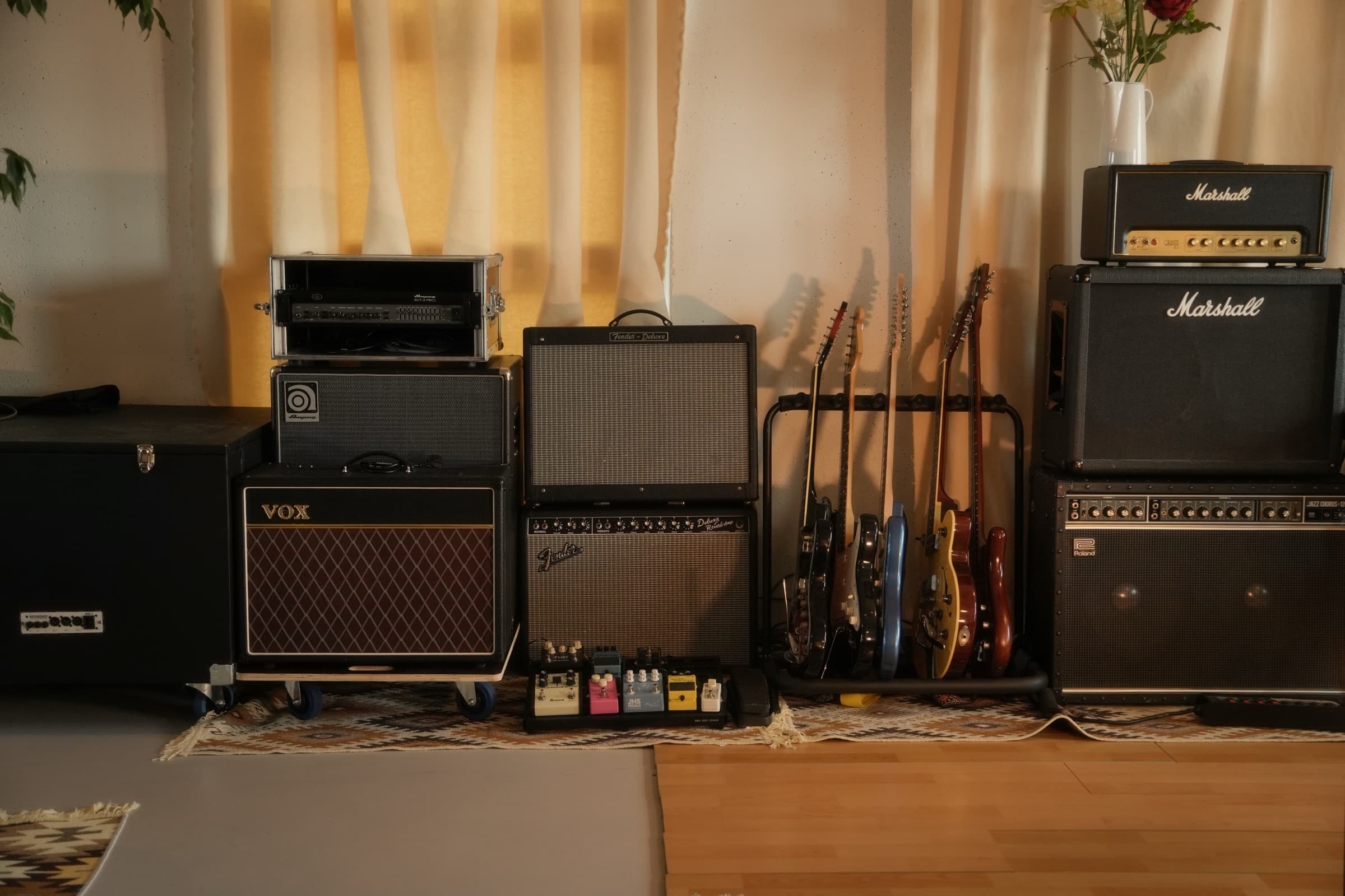 The backline wall — Vox, Fender, Ampeg and Marshall stacked with guitars racked between